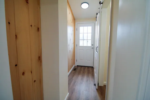 a view of an empty room with wooden floor and closet