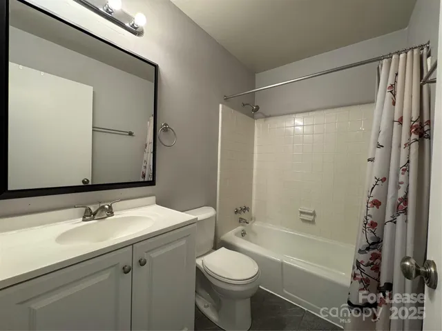 an empty room with a chandelier fan and windows