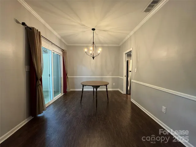 a dining room with wooden floor a chandelier a glass table and chairs
