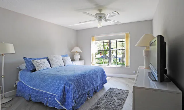 a bedroom with a large bed and a flat tv screen on dresser