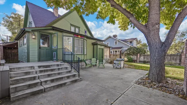 a view of a house with a small yard and a large tree