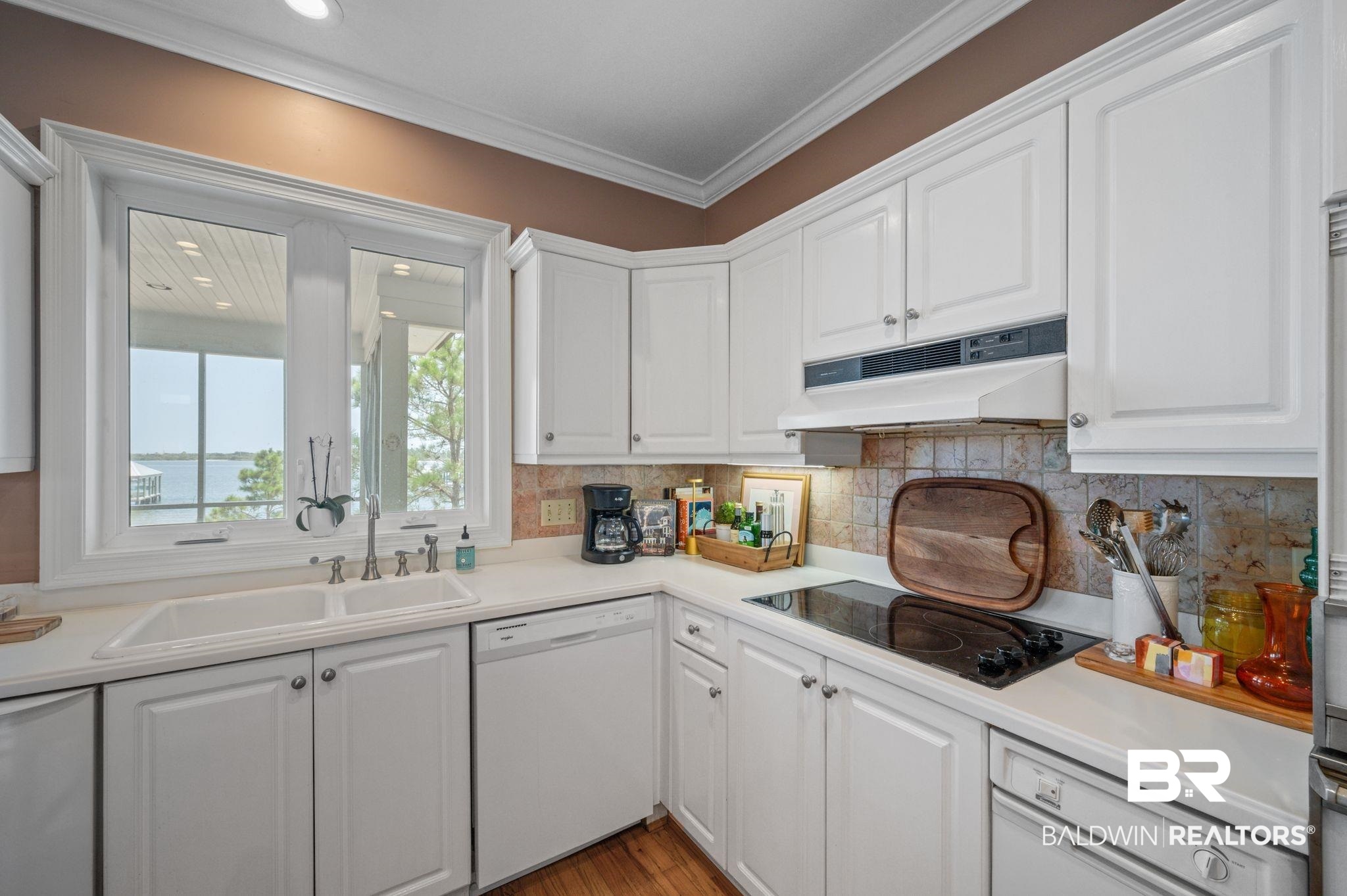 31800 River Road Orange Beach, AL 36561 - Photo 9 of 69 Kitchen with backsplash, white dishwasher, light hardwood / wood-style floors, white cabinetry, and crown molding