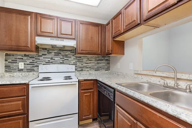 a kitchen with granite countertop a stove sink and cabinets