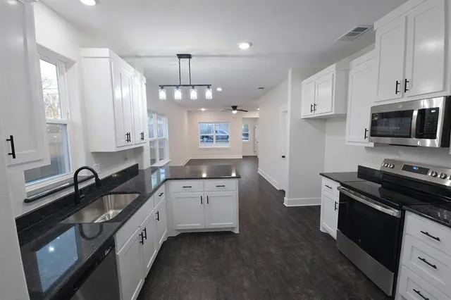 a kitchen with granite countertop a sink a stove and cabinets