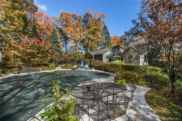a backyard of a house with table and chairs under an umbrella