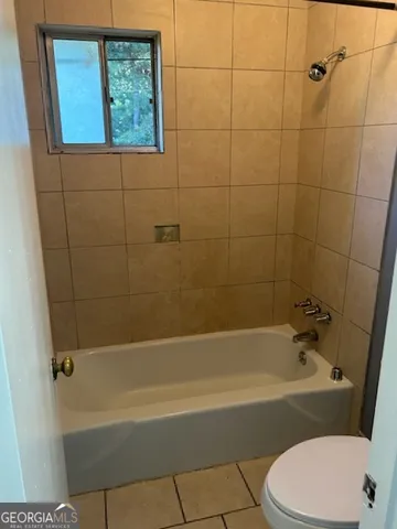 a white bath tub sitting next to a white toilet and a shower