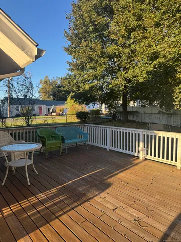 a balcony with wooden floor table and chairs