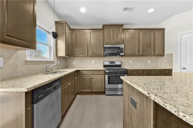 a kitchen with stainless steel appliances granite countertop a sink stove and refrigerator