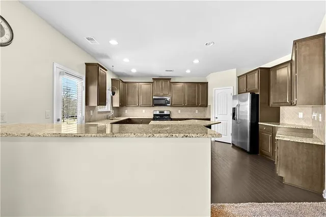 a kitchen with stainless steel appliances granite countertop a refrigerator a stove a sink and a oven