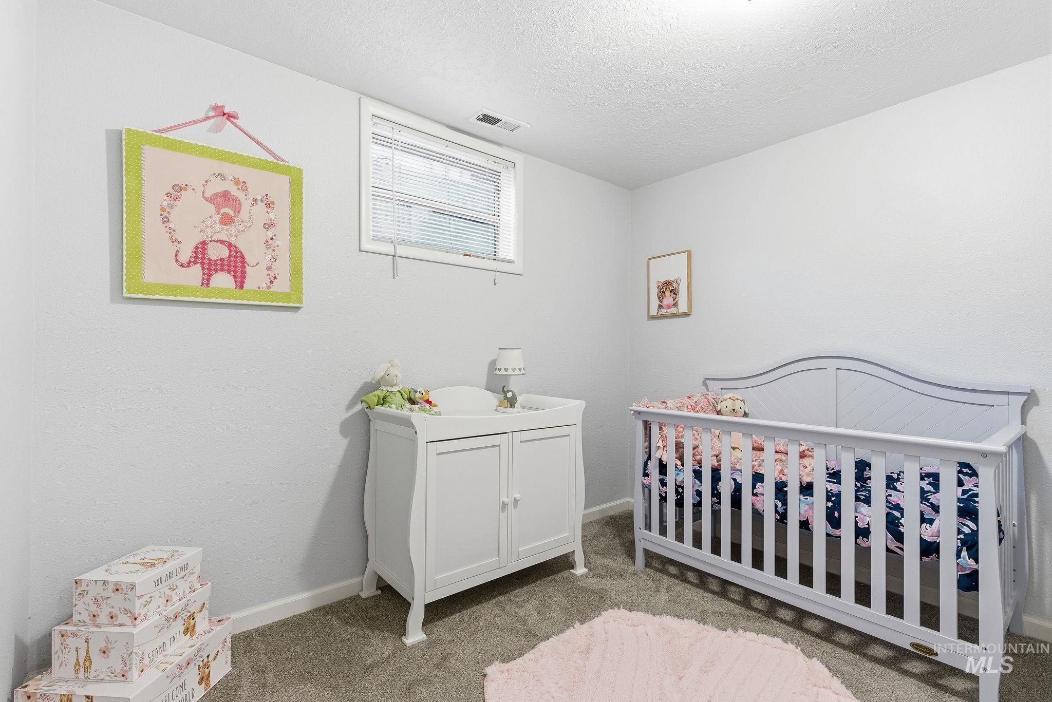 2103 West Bannock Street Boise, ID 83702 - Photo 27 of 49 Carpeted bedroom featuring a nursery area and a textured ceiling