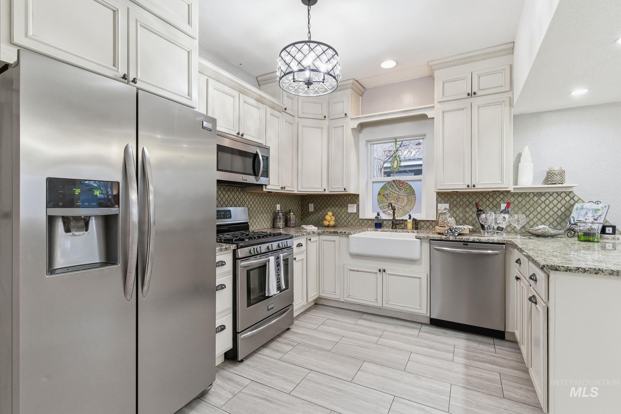 2103 West Bannock Street Boise, ID 83702 - Photo 9 of 49 Kitchen featuring appliances with stainless steel finishes, light stone countertops, recessed lighting, a chandelier, and hanging light fixtures