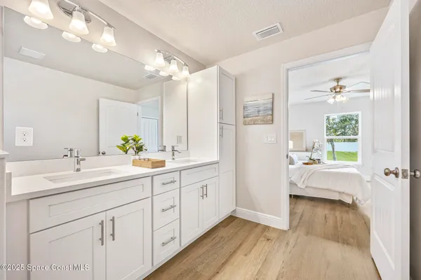 a spacious bathroom with a double vanity sink a mirror a bathtub and next to a window