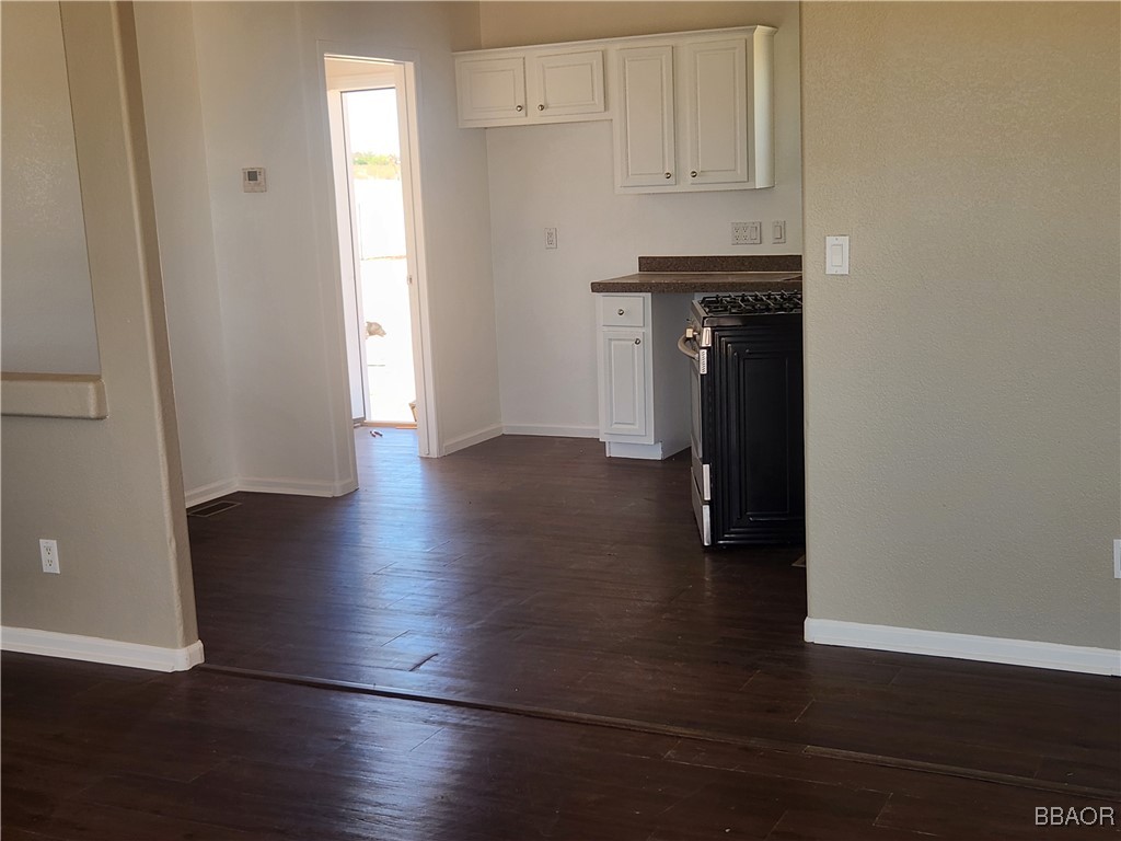 60824 Stagemans Road Landers, CA 92285 - Photo 3 of 6 an empty room with wooden floor and cabinets