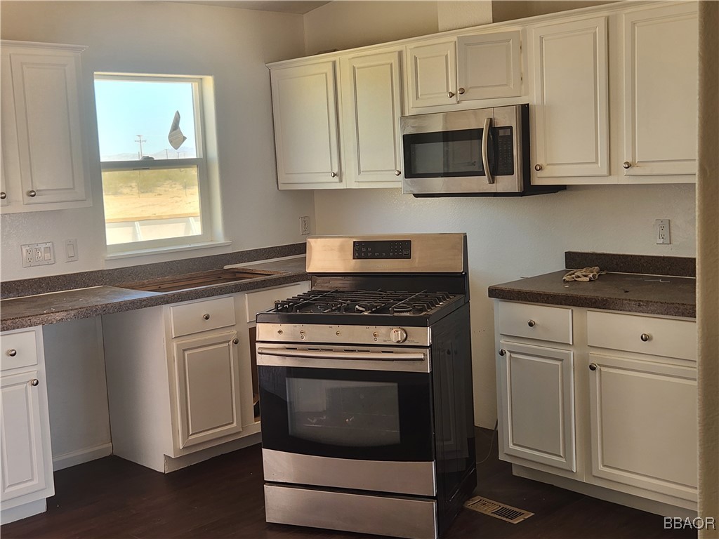 60824 Stagemans Road Landers, CA 92285 - Photo 4 of 6 a kitchen with white cabinets and appliances