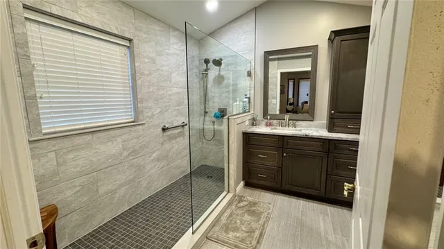 a bathroom with a granite countertop sink mirror and a shower