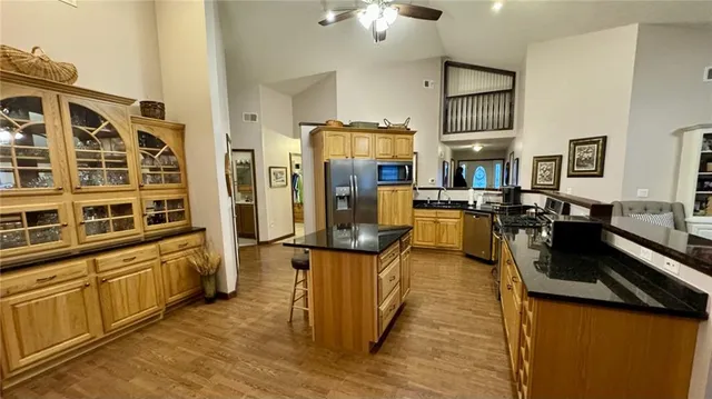 a view of a kitchen with kitchen island stainless steel appliances refrigerator stove microwave and cabinets