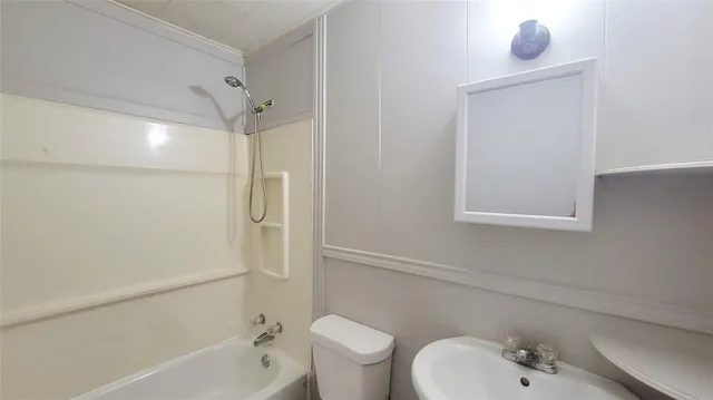 a bathroom with a bathtub shower sink vanity and toilet