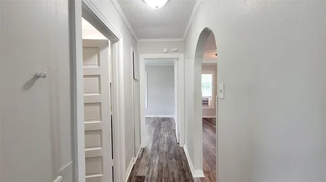 a view of a hallway with wooden floor and a bathroom