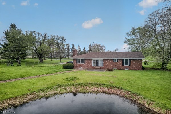 8675 West Smith Road Medina, OH 44256 - Photo 20 of 25 Brick ranch-style residence featuring a shingled roof, black window shutters, a front entry with a small porch, and a large grassy yard