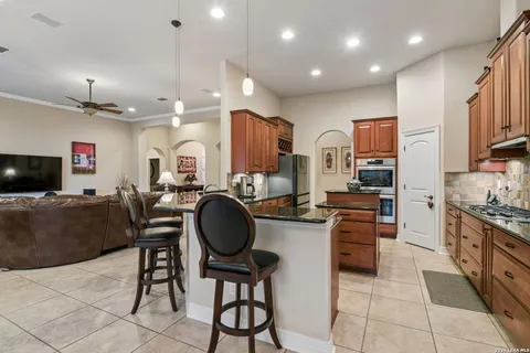 a kitchen with stainless steel appliances granite countertop a stove top oven a sink a dining table and chairs with wooden floor