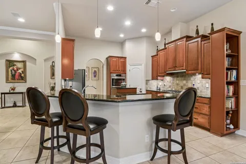 a kitchen with granite countertop a table chairs stove and cabinets