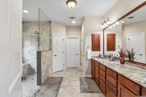 a spacious bathroom with a granite countertop sink mirror and a shower