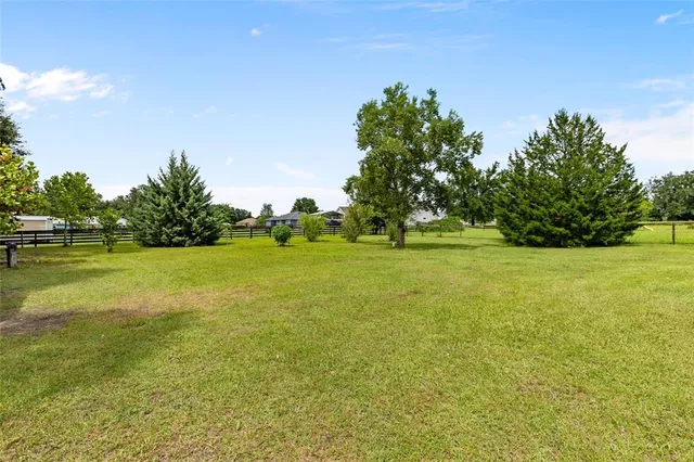 a view of a green field with wooden fence