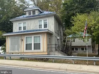 a view of a white house with a small yard and large tree