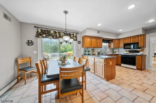 a kitchen with stainless steel appliances granite countertop a stove top oven a sink dishwasher a dining table and chairs with wooden floor