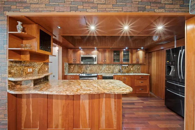 a kitchen with stainless steel appliances granite countertop a sink and wooden cabinets
