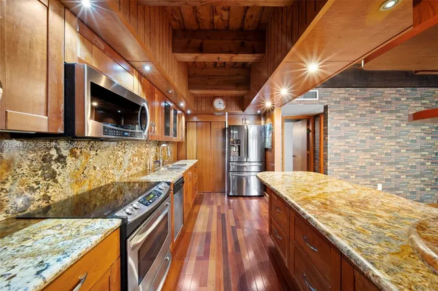 a kitchen with stainless steel appliances granite countertop a sink a stove and a wooden floors