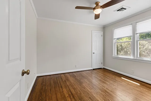 a view of empty room with wooden floor and fan