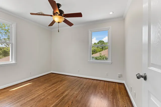 a view of empty room with wooden floor and fan