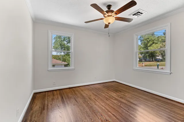 a view of an empty room with window and wooden floor