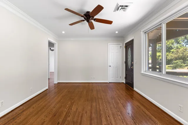 an empty room with wooden floor and windows