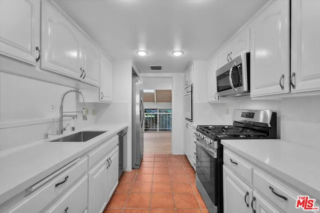 a kitchen with stainless steel appliances a sink stove and cabinets