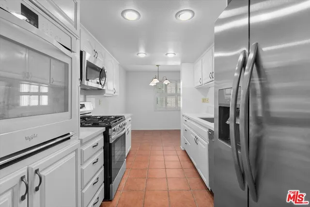 a kitchen with stainless steel appliances granite countertop a refrigerator a sink a stove and white cabinets