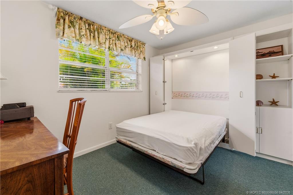 1941 Southwest Palm City Road, Unit B Stuart, FL 34994 - Photo 14 of 40 a bedroom with a bed and a chandelier