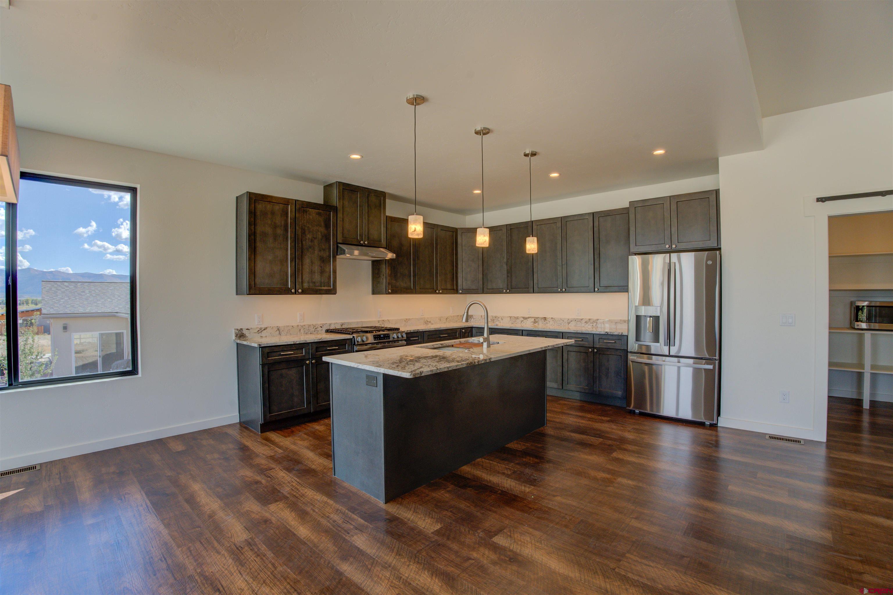 1678 Golf Course Lane Cortez, CO 81321 - Photo 7 of 28 a large kitchen with stainless steel appliances granite countertop a stove a refrigerator and a view of living room