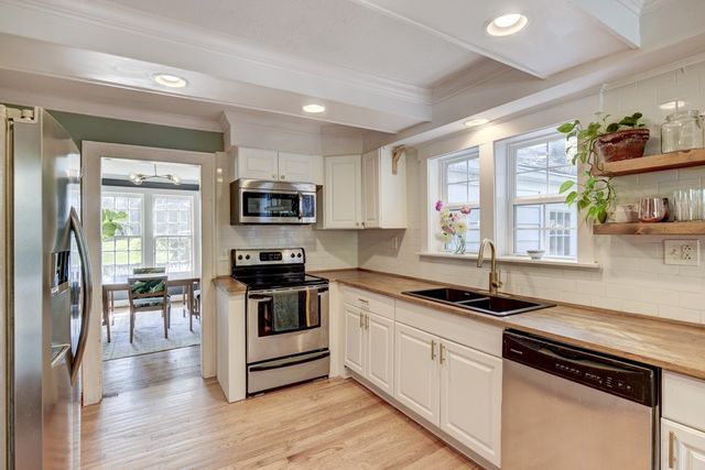 a kitchen with granite countertop stainless steel appliances a stove cabinets and wooden floor