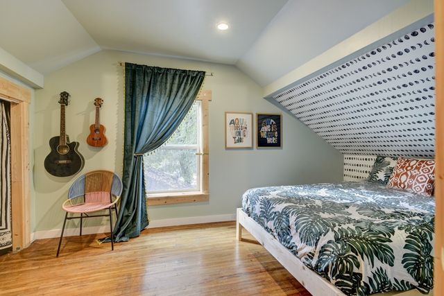 a bedroom with a bed and dresser with wooden floor