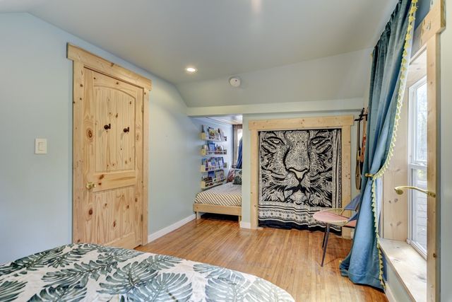 a bedroom with wooden floor and a window