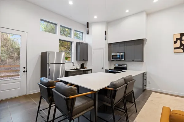 a kitchen with stainless steel appliances granite countertop a refrigerator a stove a microwave oven a sink dishwasher and white cabinets with wooden floor