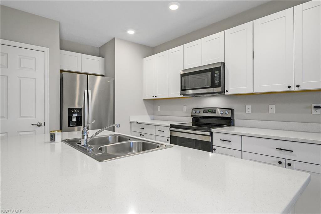 15436 Wildflower Circle Naples, FL 34119 - Photo 12 of 42 Kitchen with stainless steel appliances, white cabinets, recessed lighting, and light stone counters