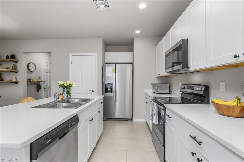 15436 Wildflower Circle Naples, FL 34119 - Photo 13 of 42 Kitchen featuring stainless steel appliances, white cabinets, an island with sink, light tile patterned floors, and recessed lighting