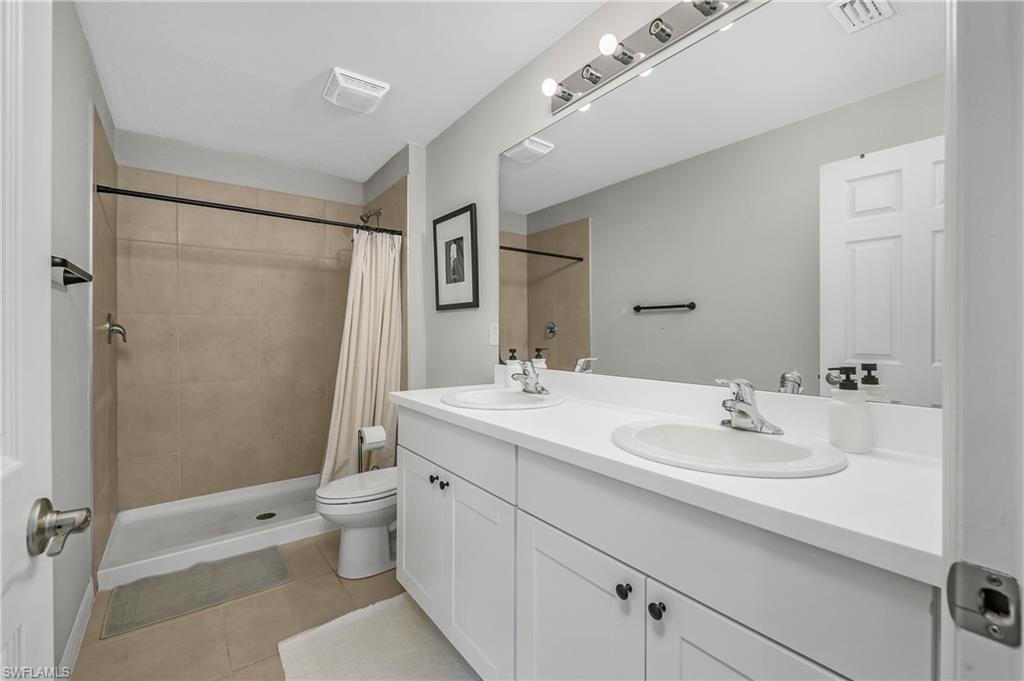 15436 Wildflower Circle Naples, FL 34119 - Photo 25 of 42 Full bathroom with a shower stall, double vanity, and light tile patterned flooring