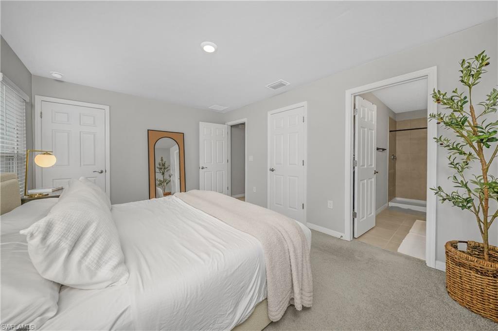 15436 Wildflower Circle Naples, FL 34119 - Photo 27 of 42 Bedroom featuring light colored carpet and ensuite bath