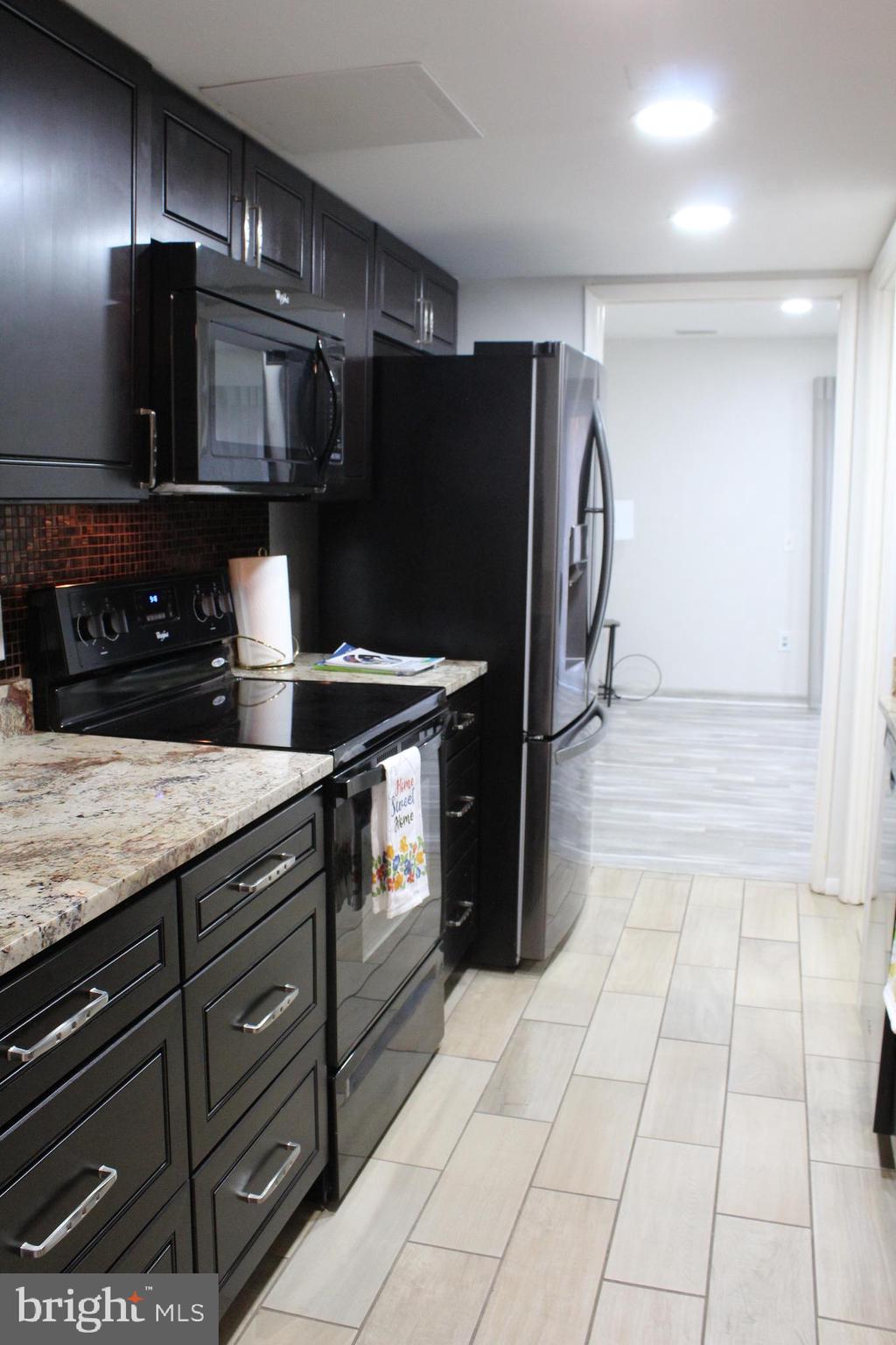 15002 Eardley Court, Unit 282B Silver Spring, MD 20906 - Photo 7 of 28 a kitchen with granite countertop a refrigerator and a stove top oven