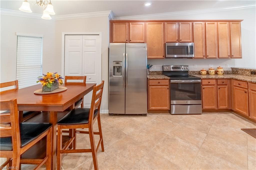 9521 Avellino Way, Unit 2426 Naples, FL 34113 - Photo 4 of 46 a kitchen with stainless steel appliances granite countertop a stove a refrigerator a sink a dining table and chairs
