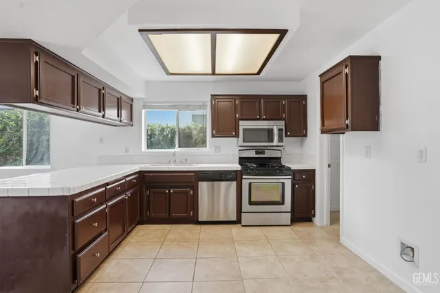 a kitchen with stainless steel appliances granite countertop a stove top oven a sink a counter space and cabinets